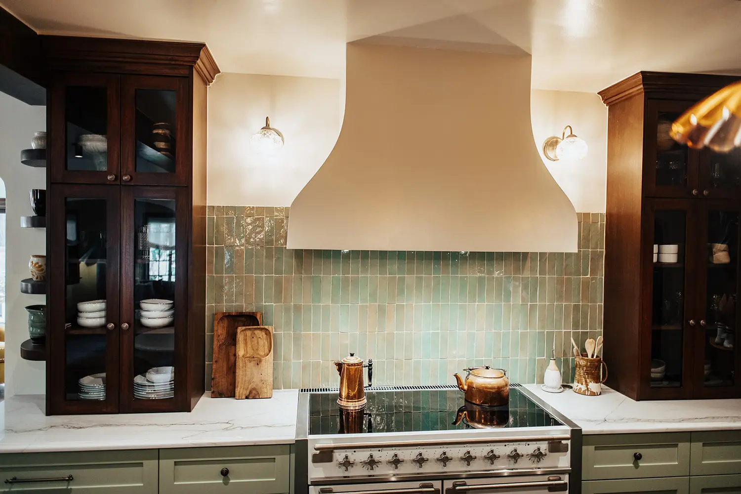Close detail of custom plaster hood, glass display cabinets, and green tile in an award-winning Utah kitchen