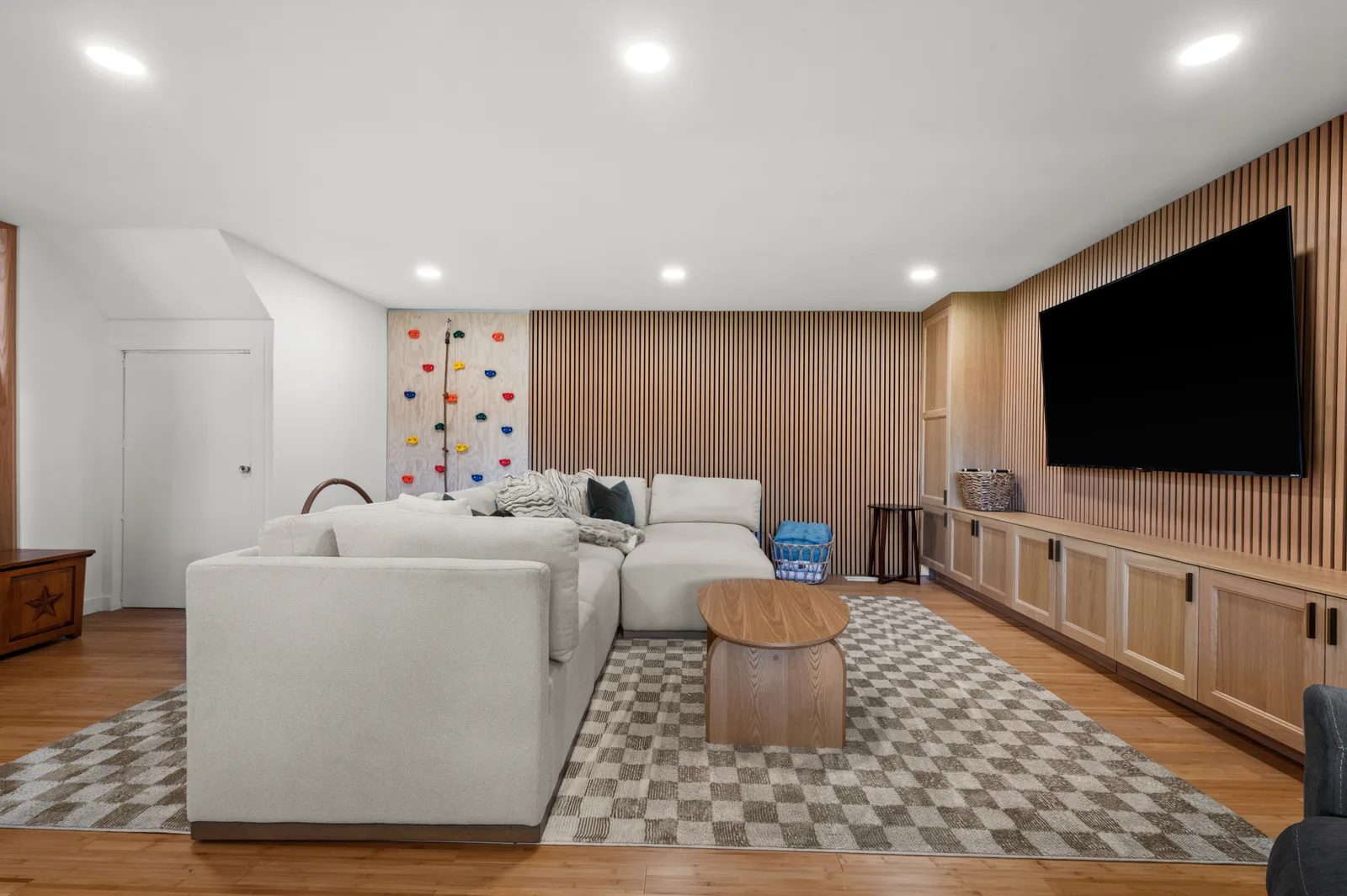Finished lower-level family room with a wood-slat media wall and built-in cabinetry in a Holladay home remodel