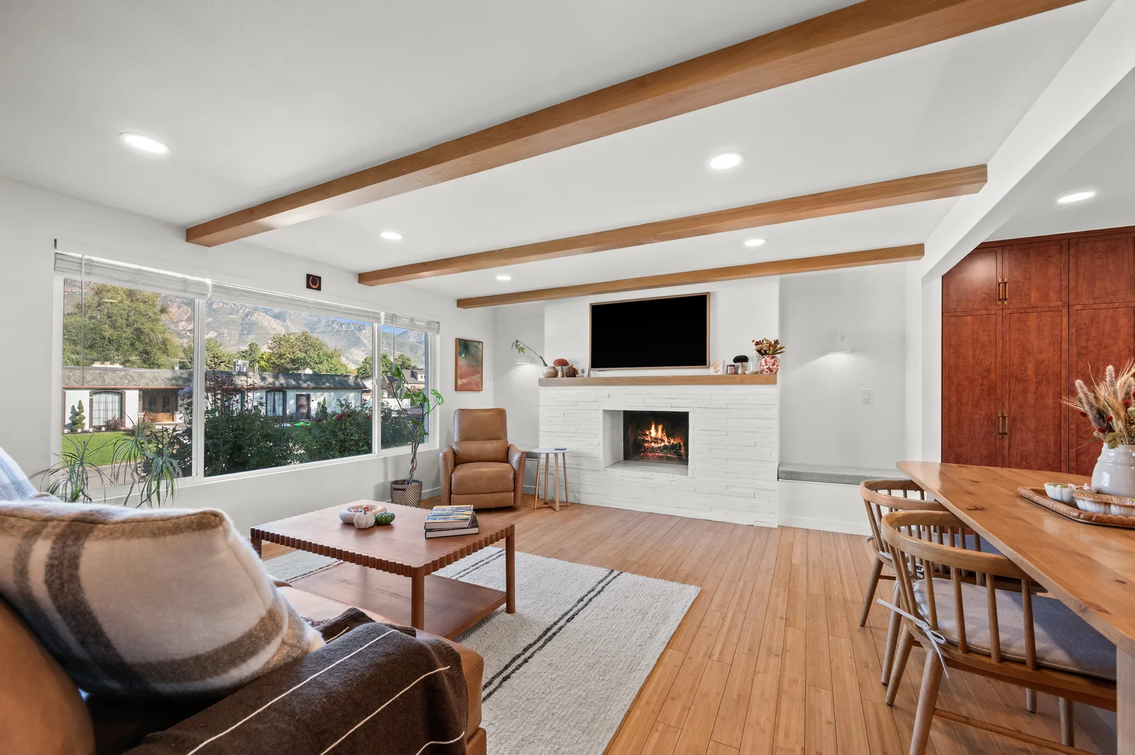 Open living room with a fireplace and mountain view through new windows in a remodeled Holladay mid-century home